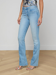 Wearing the Ruth Straight-Leg Jean in a light blue, vintage wash with slight fading, styled with a floral top and silver open-toe heels, a person stands against a plain white background.
