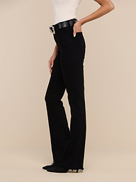 Woman wearing a sleeveless top, Ruth Straight-Leg Jean in black high-rise stretch denim, a black belt with a large buckle, and black shoes, standing against a plain white background.