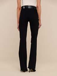 A person wearing the Ruth Straight-Leg Jean in black stretch denim, paired with a white top and black heels, stands facing away from the camera against a plain white background.