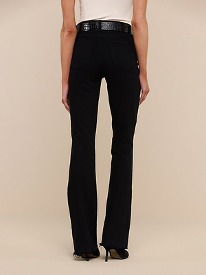 A person wearing Ruth Straight-Leg Jean in black, a white sleeveless top, a black textured belt, and black heeled shoes stands facing away from the camera against a plain beige background.