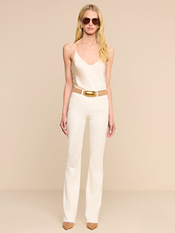 A woman wearing sunglasses, a beige camisole, the Ruth Straight-Leg Jean in stretch denim with a belt, and brown pointed-toe heels stands against a plain white background.