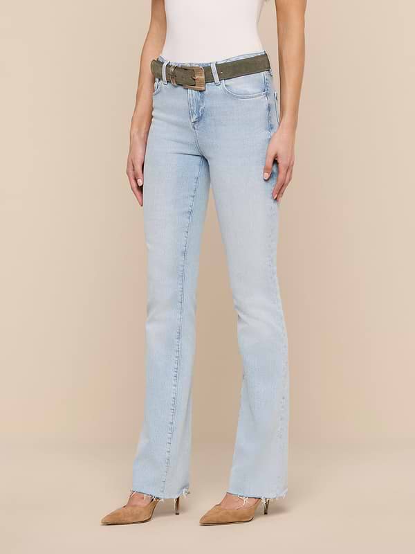 A woman wearing the Ruth Straight-Leg Jean in light blue with a raw hem, paired with a white sleeveless top, brown pointed-toe heels, and a camouflage belt, stands against a plain white background. Her head is not visible in the image.