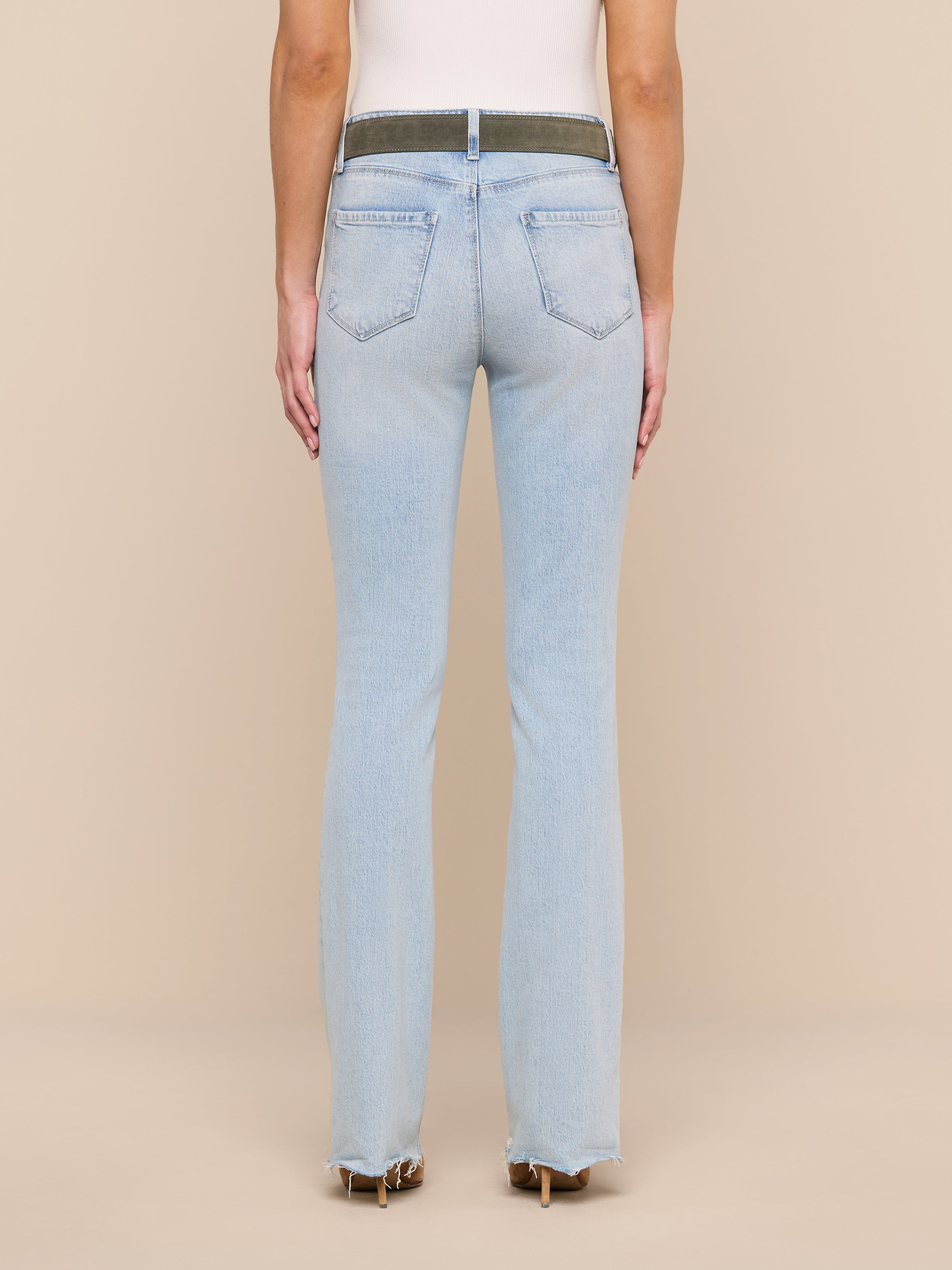 A person is shown from the back, modeling the Ruth Straight-Leg Jean in light blue, featuring back pockets and a contrasting waistband, styled with heeled shoes against a plain white background.