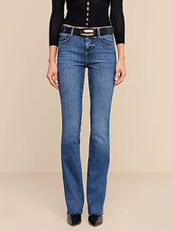 Wearing the Ruth Straight-Leg Jean in a medium indigo wash, styled with a black belt, black pointed shoes, and a black long-sleeve top, the model is shown from shoulders down against a plain white background.