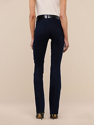 A person stands facing away, wearing a white sleeveless top, the Ruth Straight-Leg Jean in an ultra dark indigo wash, a black belt, and tan heels against a plain white background.