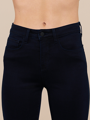 A close-up of a person’s midsection wearing Ruth Straight-Leg Jeans in ultra dark indigo, made from super stretch denim with a button and zipper closure, front pockets, and belt loops. The person’s bare torso is visible above the waistband.