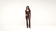 A woman wearing sunglasses, a brown long-sleeve top, brown pants, and brown shoes stands against a plain white background.