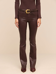 A person wearing a fitted brown long-sleeve top, the Ruth Coated Straight-Leg Jean with a gold-buckled belt, and pointed brown shoes stands against a plain white background.