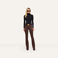 A person wearing a black turtleneck, a black belt with a large gold buckle, and Ruth Coated Straight-Leg Jean high-rise, straight-leg coated stretch denim jeans.