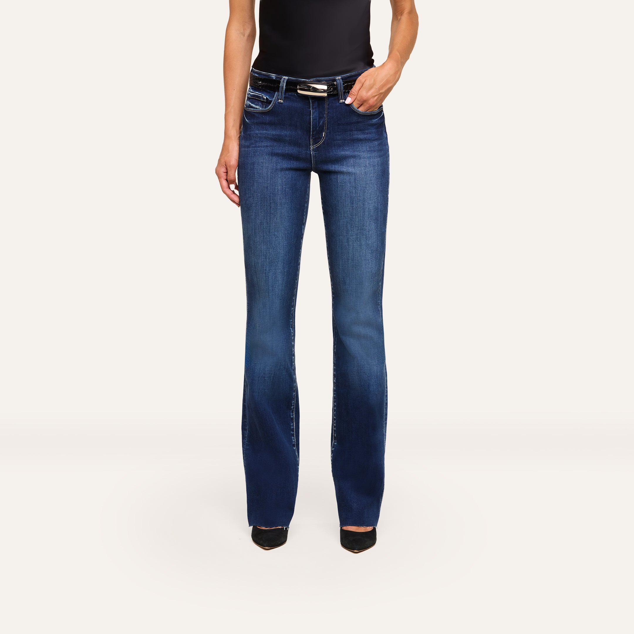 A person wearing Ruth Straight-Leg Jean, a black sleeveless top, and black pointed-toe shoes stands against a plain white background.