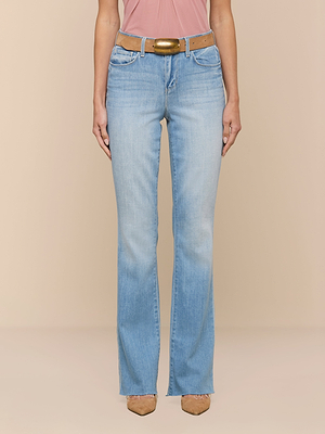 Model wearing Ruth Straight-Leg Jean in light indigo wash with a brown belt and tan pointed-toe shoes, standing against a beige background; only the torso and legs are visible.