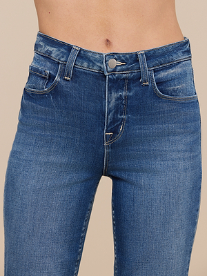 Close-up of a person wearing the Kendra Cropped Flare Jean, featuring premium stretch denim, five-pocket design, subtle waist fading, and sustainable recycled fibers. The blue high-rise cropped flare cut highlights the visible midriff.