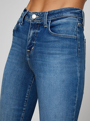 Close-up of a person wearing Kendra Cropped Flare Jean—high-waisted, blue cropped flare jeans made from premium stretch denim with a button closure, front pockets, and visible stitching at the waist and upper legs.