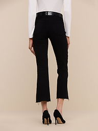 Model shown from the back against a plain light background wearing the Kendra Cropped Flare Jean in black with frayed hems, paired with black high heels and a white long-sleeve top.