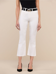 A person wearing the Kendra Cropped Flare Jean in white stretch denim, featuring a high-rise fit, cropped flare leg, and raw hem, paired with a black top and black heels stands against a plain white background. Only the lower half of the body is visible.