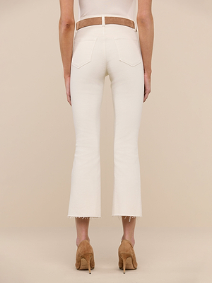 Back view of a person in Kendra Cropped Flare Jean in vintage white with raw hems, styled with a tan belt, white top, and tan heels, standing against a plain beige background.