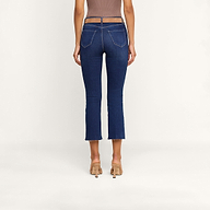 A person wearing high-heeled shoes and the Kendra Cropped Flare Jean, made from stretch denim with a sheer waistband and back pockets, is seen from behind against a plain white background.
