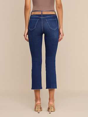 Une femme, de dos, porte un jean évasé court « Kendra » en denim stretch haut de gamme, avec des ourlets effilochés et des poches arrière, un haut sans manches taupe et des sandales à talons couleur chair, sur un fond beige.