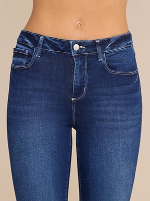 Gros plan sur une personne portant le jean « Kendra Cropped Flare » en denim stretch bleu foncé, caractérisé par une taille haute, des poches avant apparentes, un bouton, des passants de ceinture et un ventre dénudé laissant apparaître le nombril.