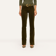 A person wearing the Stevie Velvet Jean, styled with a wide belt and taupe shoes, showcases its sleek high-rise silhouette and straight-leg fit against a plain light background. Only the lower torso and legs are visible.