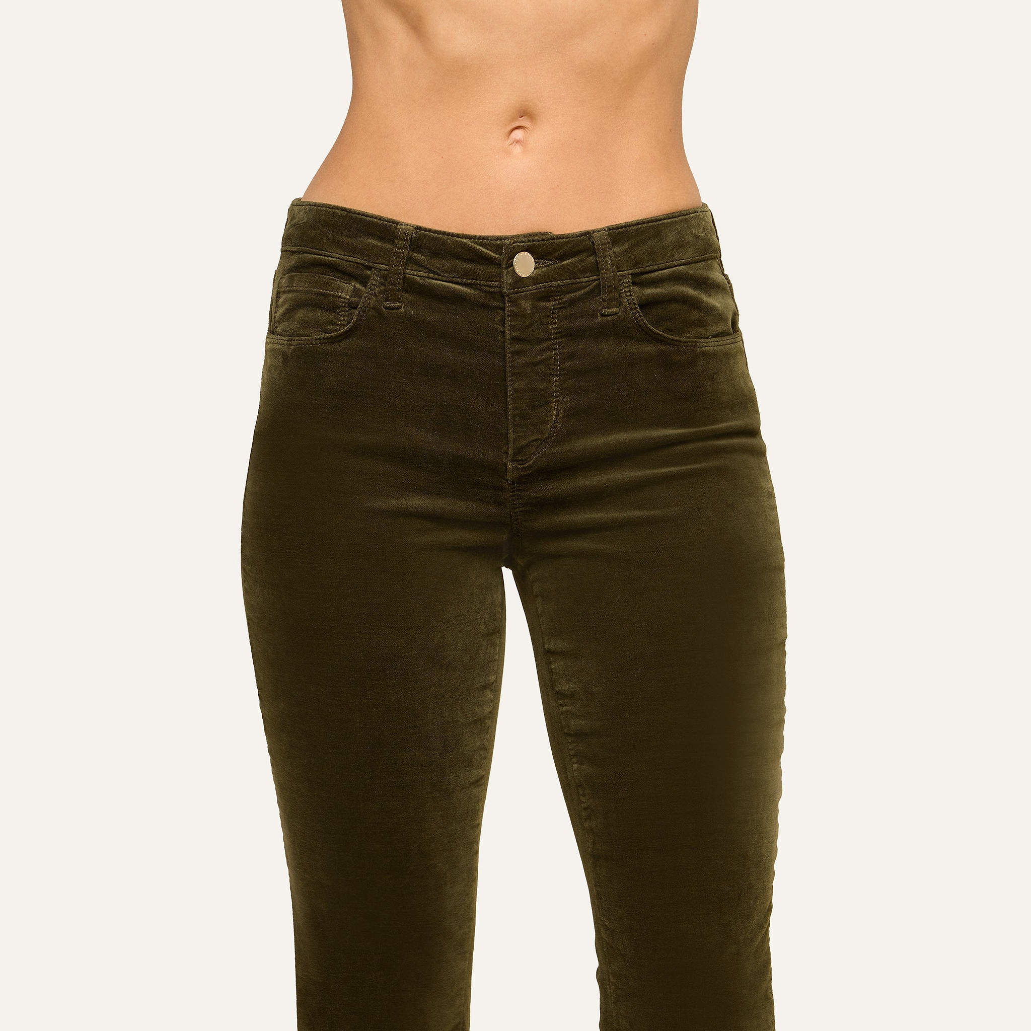 A person wearing the Stevie Velvet Jean in a high-rise, dark green stretch velvet fabric with a straight leg fit, shown from mid-torso to thighs against a plain light background.