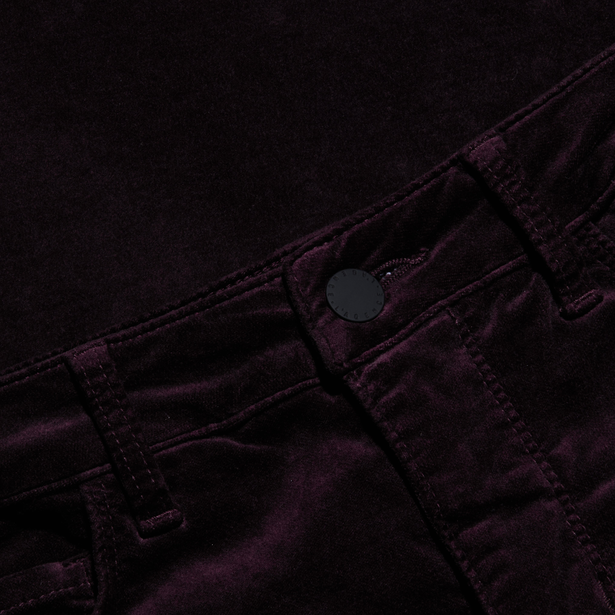 Close-up of the Stevie Velvet Jean, crafted from a soft, dark-colored velvety fabric, featuring a high-rise waistband, stitched belt loops, and a black front button.