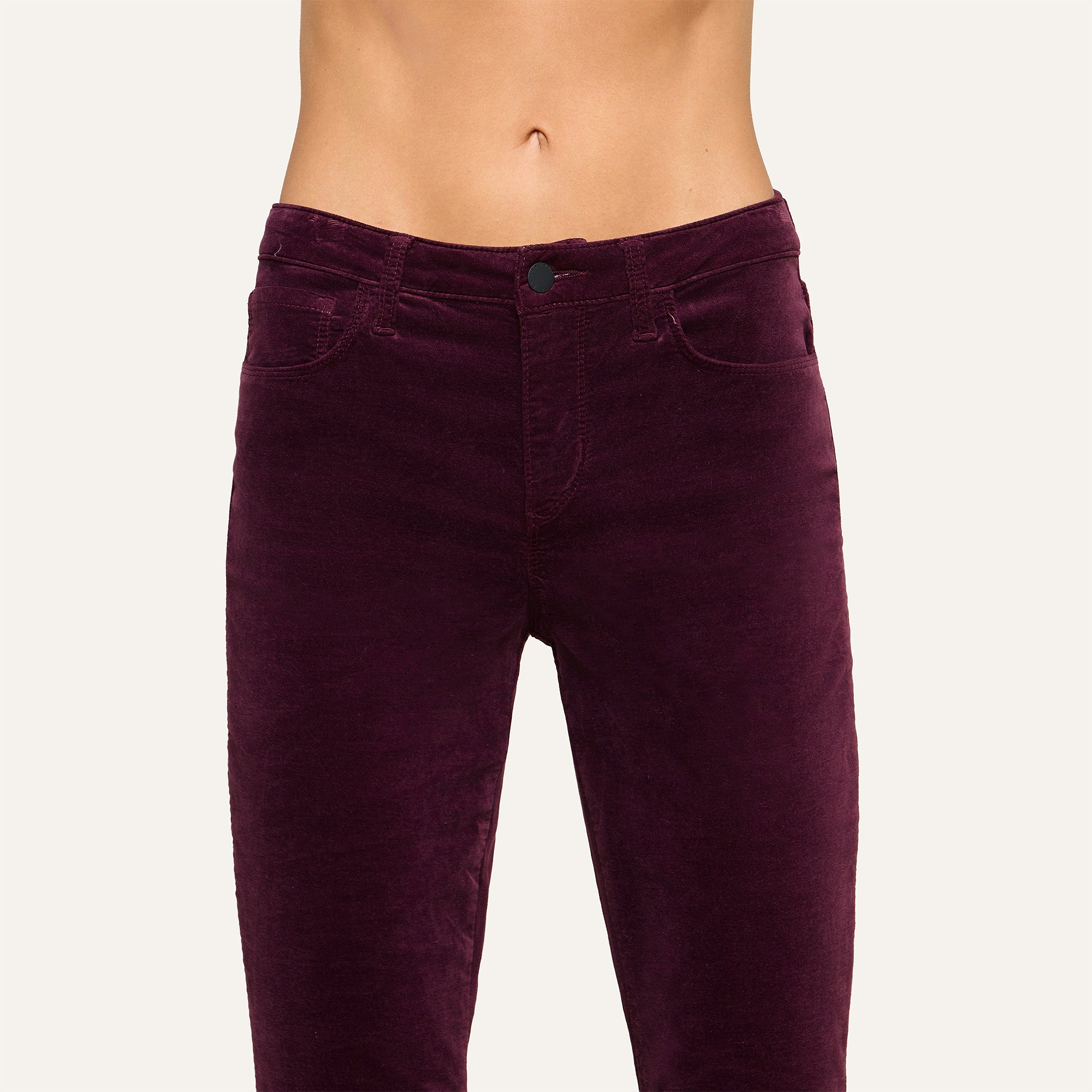 A person wearing the Stevie Velvet Jean in a dark burgundy shade, shown from waist to mid-thigh against a plain background.