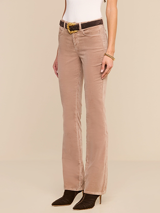 A person wearing the Stevie Velvet Jean, a white sleeveless top, a beige corduroy pant, a black belt with a gold buckle, a gold bracelet, and black pointed-toe shoes stands against a neutral background.