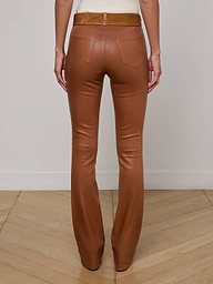 Person standing with back facing the camera, wearing the Selma Coated Bootcut Jean and a white top. The background is plain and light-colored.