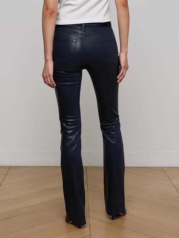 A person wearing the Selma Coated Bootcut Jean in black and a white top stands facing away, displaying the back view of the outfit against a plain white background.