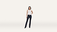 Woman stands facing forward, wearing a crisp white sleeveless top, dark blue jeans, and black shoes, with one hand on her hip against a plain white background.