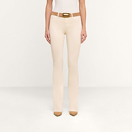 A person wearing the Selma Coated Bootcut Jean in beige, paired with a white top, a tan belt with a gold buckle, and tan pointed-toe shoes stands against a plain white background. Only the lower body is visible.