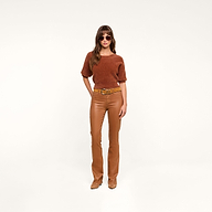 A woman wearing sunglasses, a dark java brown short-sleeve top, tan boots, and the Selma Coated Bootcut Jean stands confidently against a plain white background.