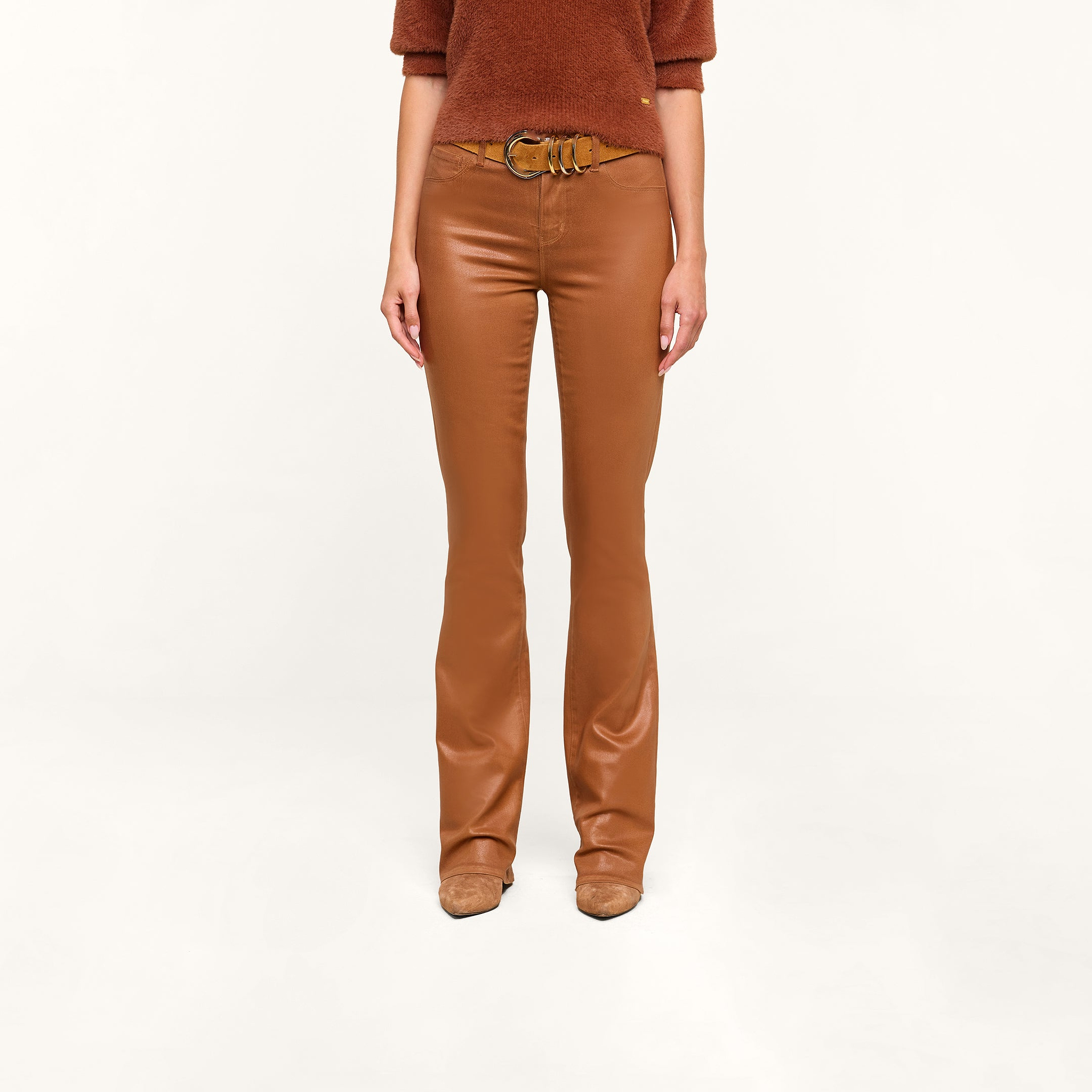 A person wearing a dark java brown sweater, the Selma Coated Bootcut Jean, and tan shoes stands against a plain white background.