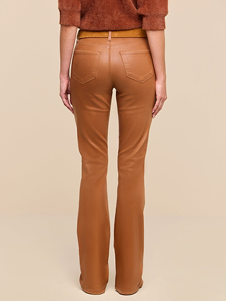 A person stands facing away against a neutral beige background, wearing the Selma Coated Bootcut Jean in tan faux leather and a brown fuzzy sweater in a deep dark java hue, with their arms relaxed at their sides.
