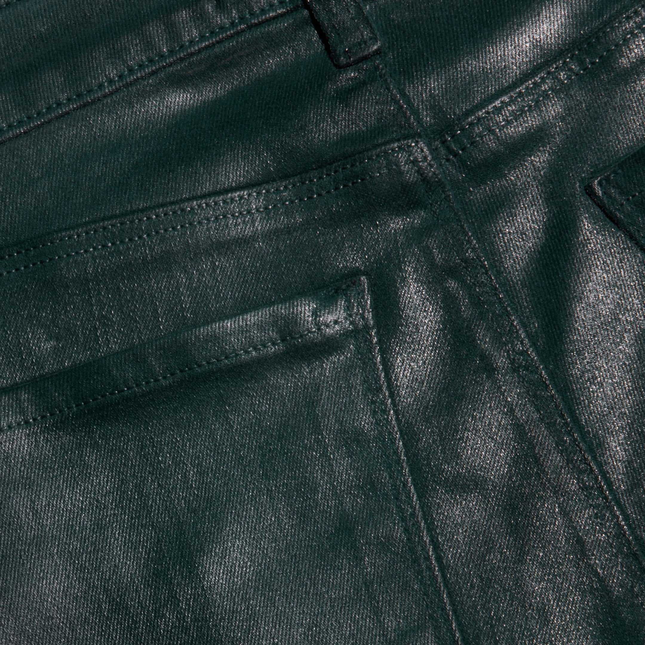 Close-up of the Selma Coated Bootcut Jean in dark green, highlighting the textured coating, detailed stitching, and upper section of the front pocket and belt loop.