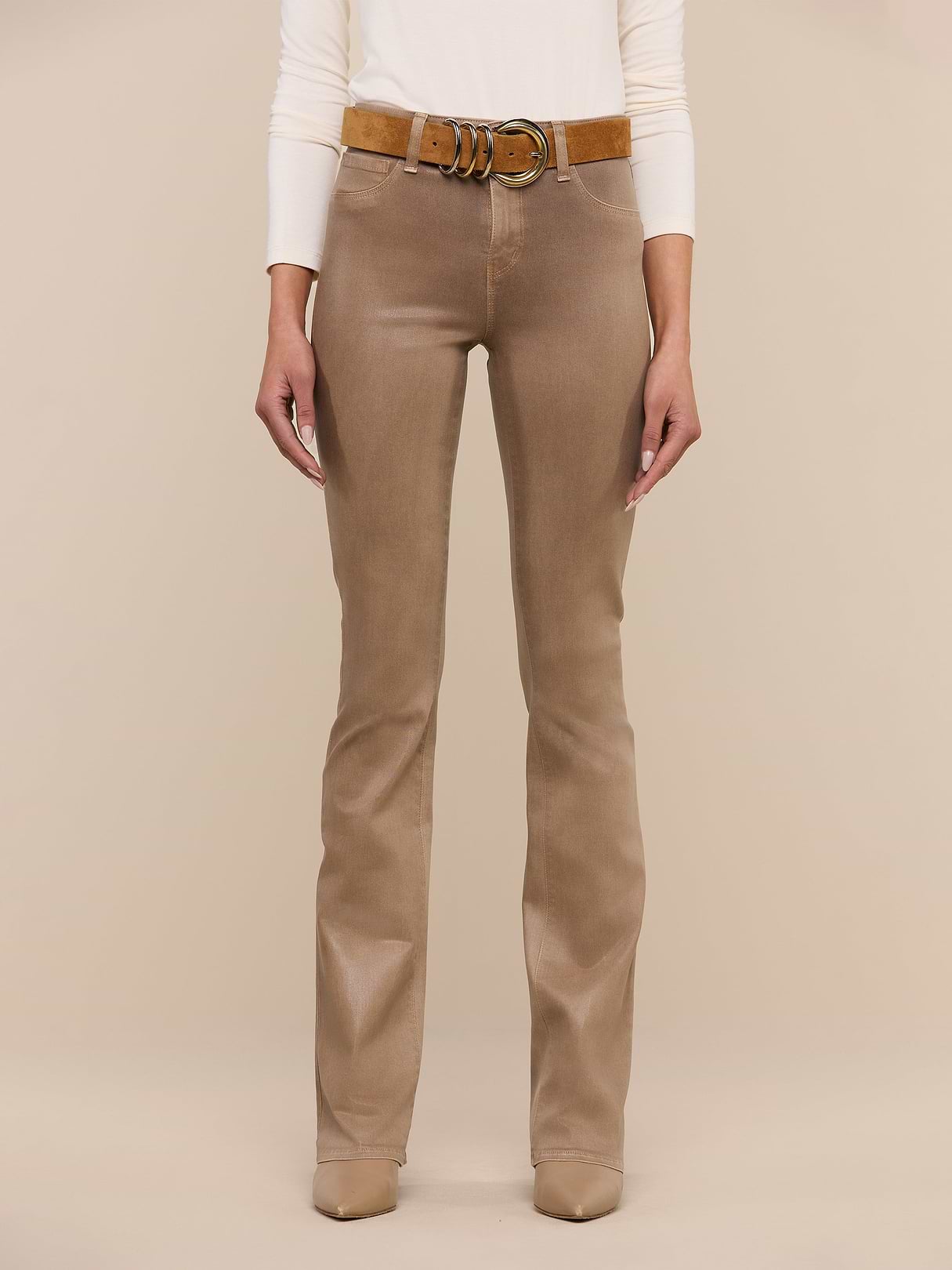 A person wearing the Selma Coated Bootcut Jean, styled with a brown belt and beige shoes, stands against a plain white background. Only the lower half of the body is visible.
