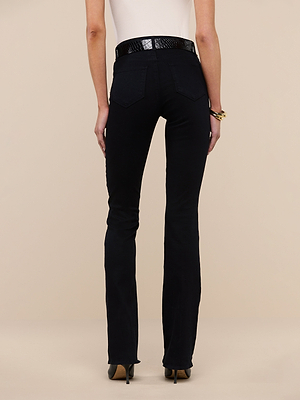 A person is shown from the back, wearing a white sleeveless top and true-black Selma Bootcut Jean with a black textured belt, standing against a plain beige background.