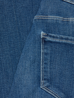 Close-up of the Selma Bootcut Jean in blue denim, featuring a back pocket and seam details. The light contrasting stitching highlights the super stretch fabric for enhanced comfort and stylish appeal.