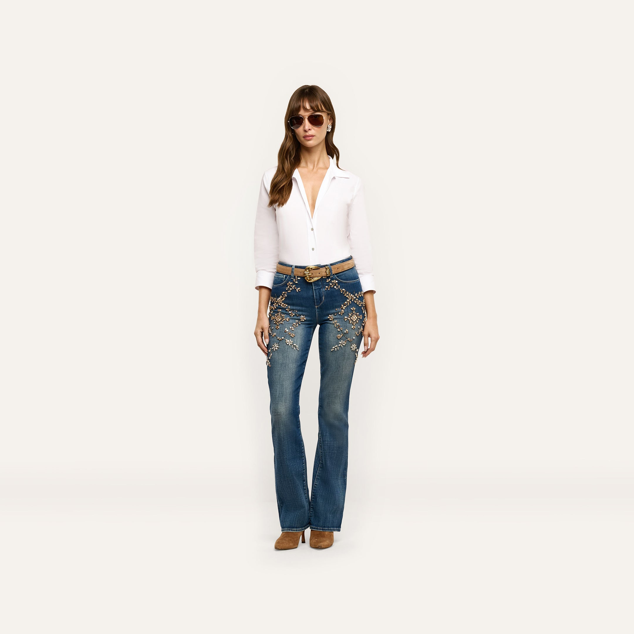 A woman wearing a white collared shirt and Selma Embellished Bootcut Jean with floral beadwork at the hips.