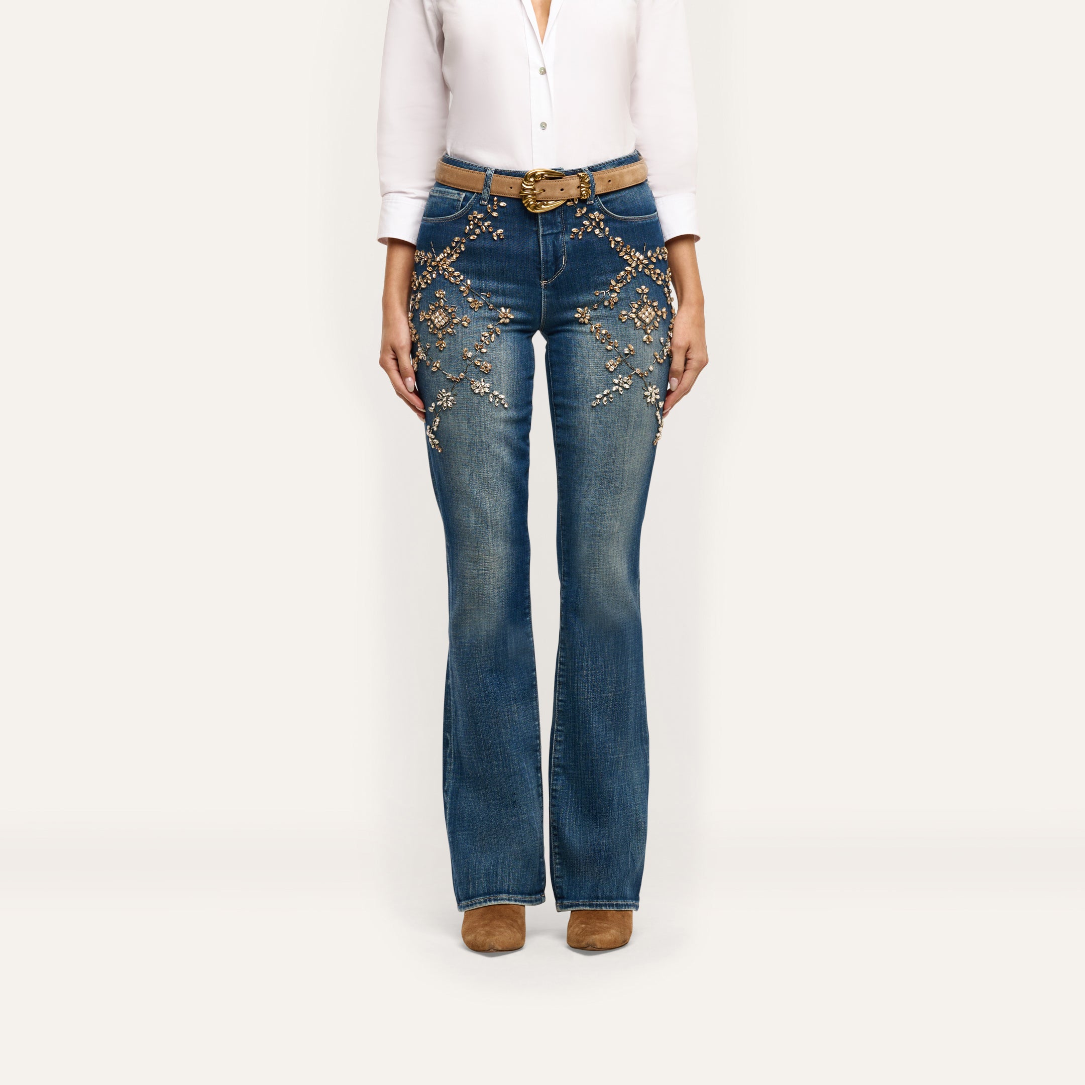 Selma Embellished Bootcut Jean in blue, featuring floral embroidery and crystal details on the hips and thighs, worn with a tan belt and ankle boots.