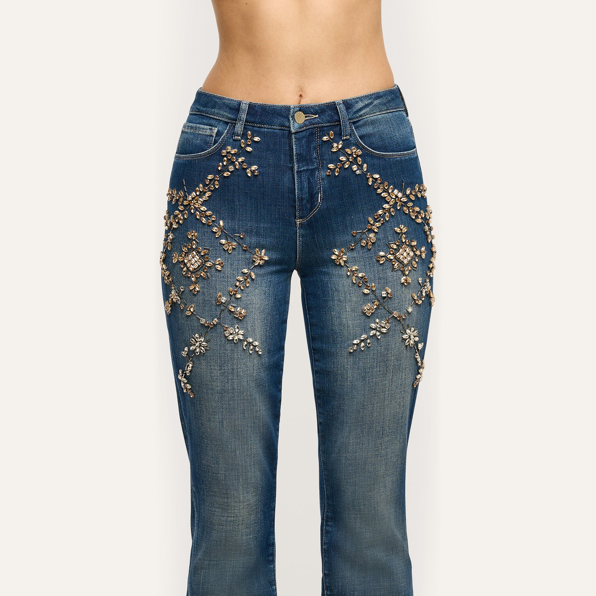 Selma Embellished Bootcut Jean in medium-wash denim, featuring floral-patterned crystal and bead embellishments on the hips and thighs.