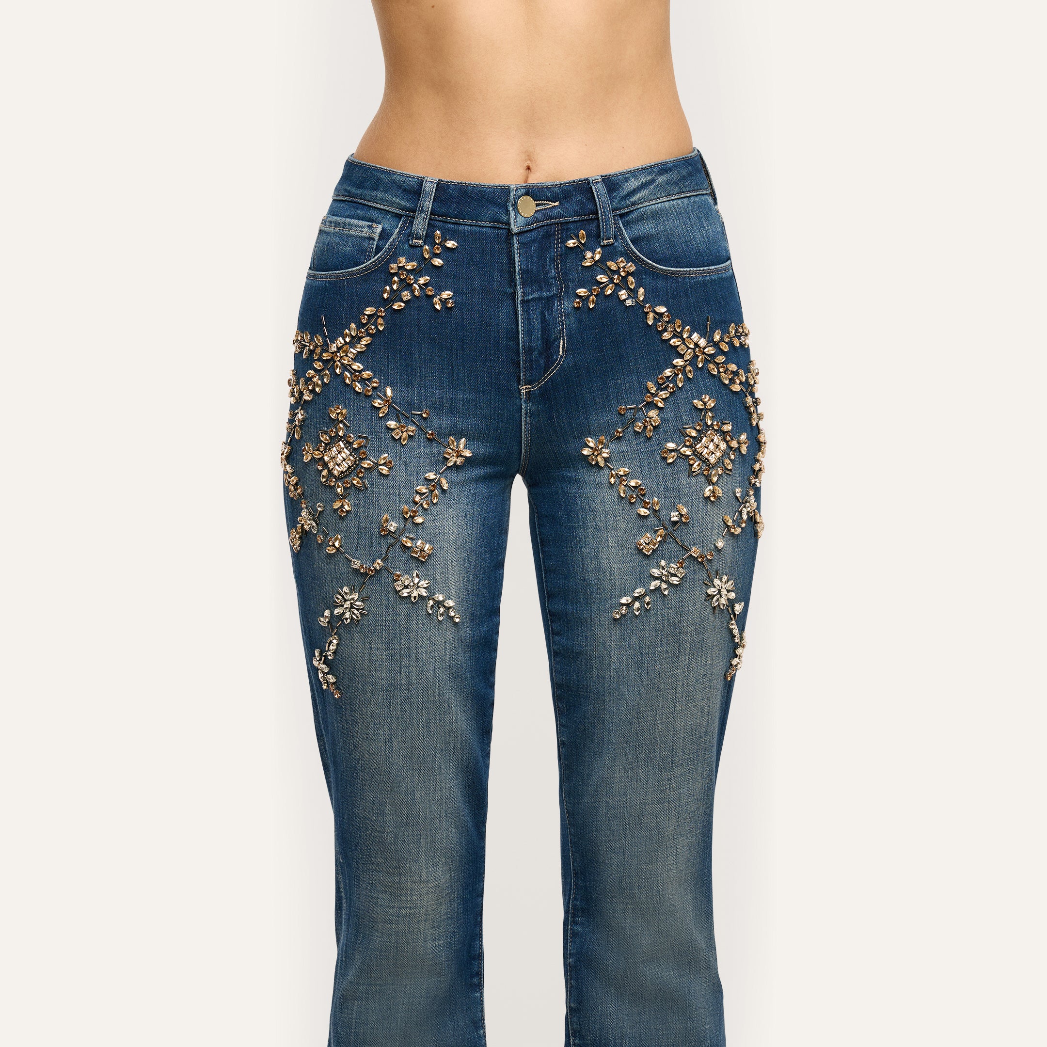 Selma Embellished Bootcut Jean in medium-wash denim, featuring floral-patterned crystal and bead embellishments on the hips and thighs.