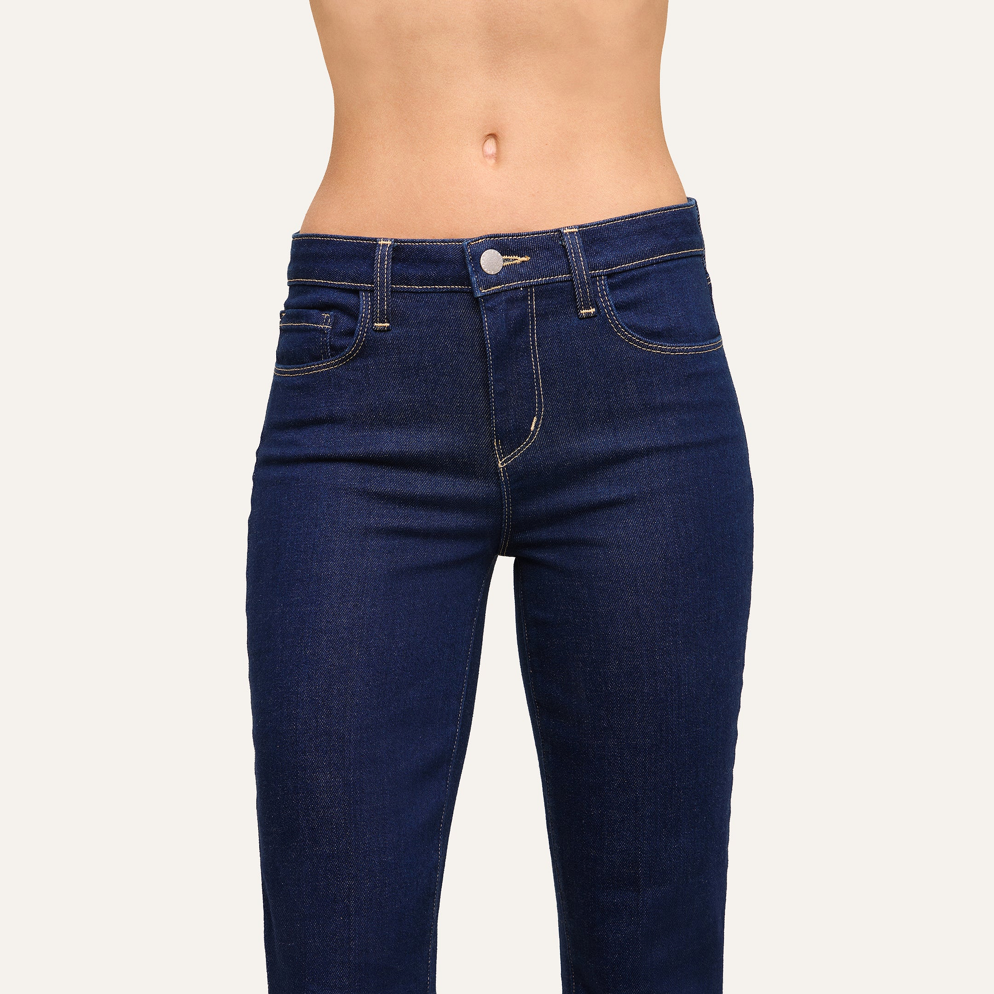 A person is shown from mid-torso to upper thighs wearing the Selma Bootcut Jean in dark blue stretch denim with yellow stitching against a plain background.