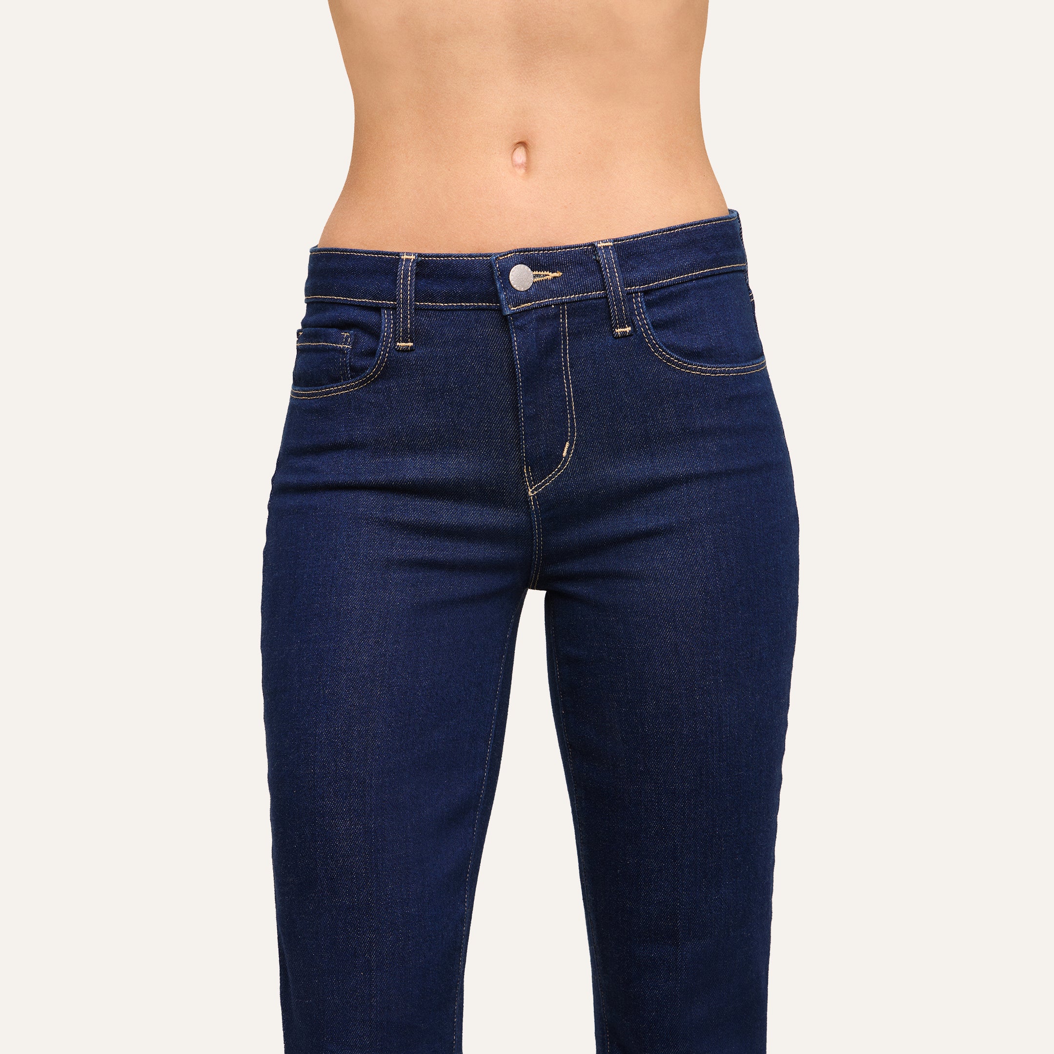 A person is shown from mid-torso to upper thighs wearing the Selma Bootcut Jean in dark blue stretch denim with yellow stitching against a plain background.