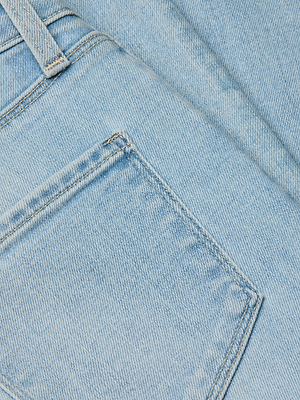 Close-up of light blue stretch denim fabric, highlighting the texture and detail of the Monique Skinny Jean’s high rise pocket and seam with visible stitching.
