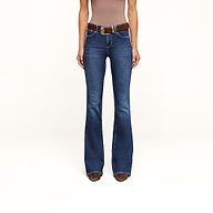 A person wearing a brown sleeveless top, the high-rise Marty Flare Jean crafted from stretch denim with a brown belt, and brown pointed-toe shoes stands against a plain white background.