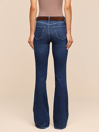 A person shown from the back against a plain beige background wears the Marty Flare Jean—high-waisted, dark blue flare-leg jeans crafted from stretch denim—paired with a brown belt.