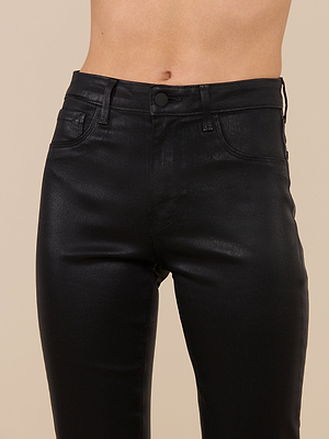 Cropped image of a person wearing Marty Coated Flare Jean in black, high rise faux leather, against a beige background, focusing on the waist and upper thighs.