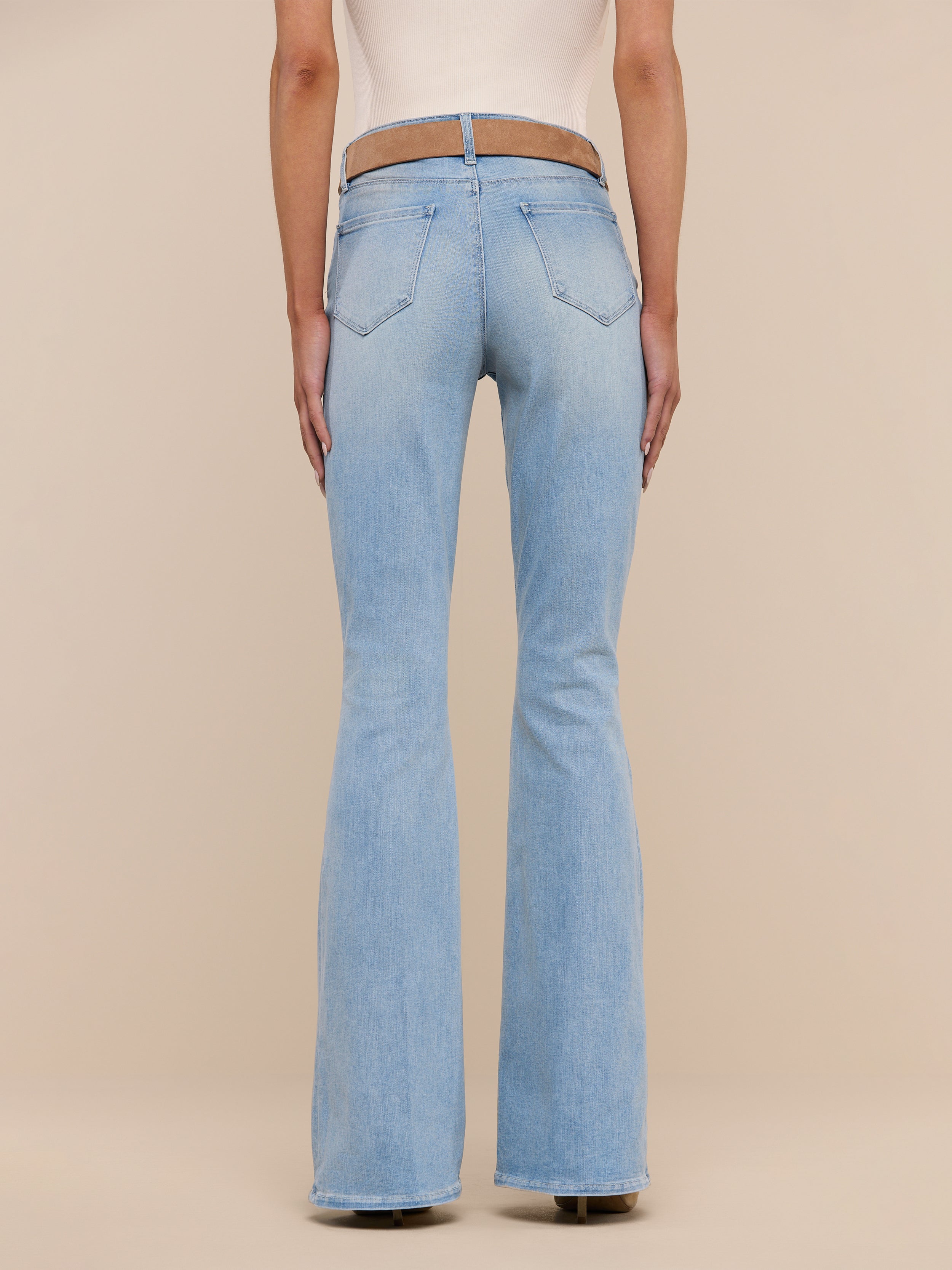 A person wearing the Marty Flare Jean in light blue with a beige top, shown from the back and standing against a plain white background.